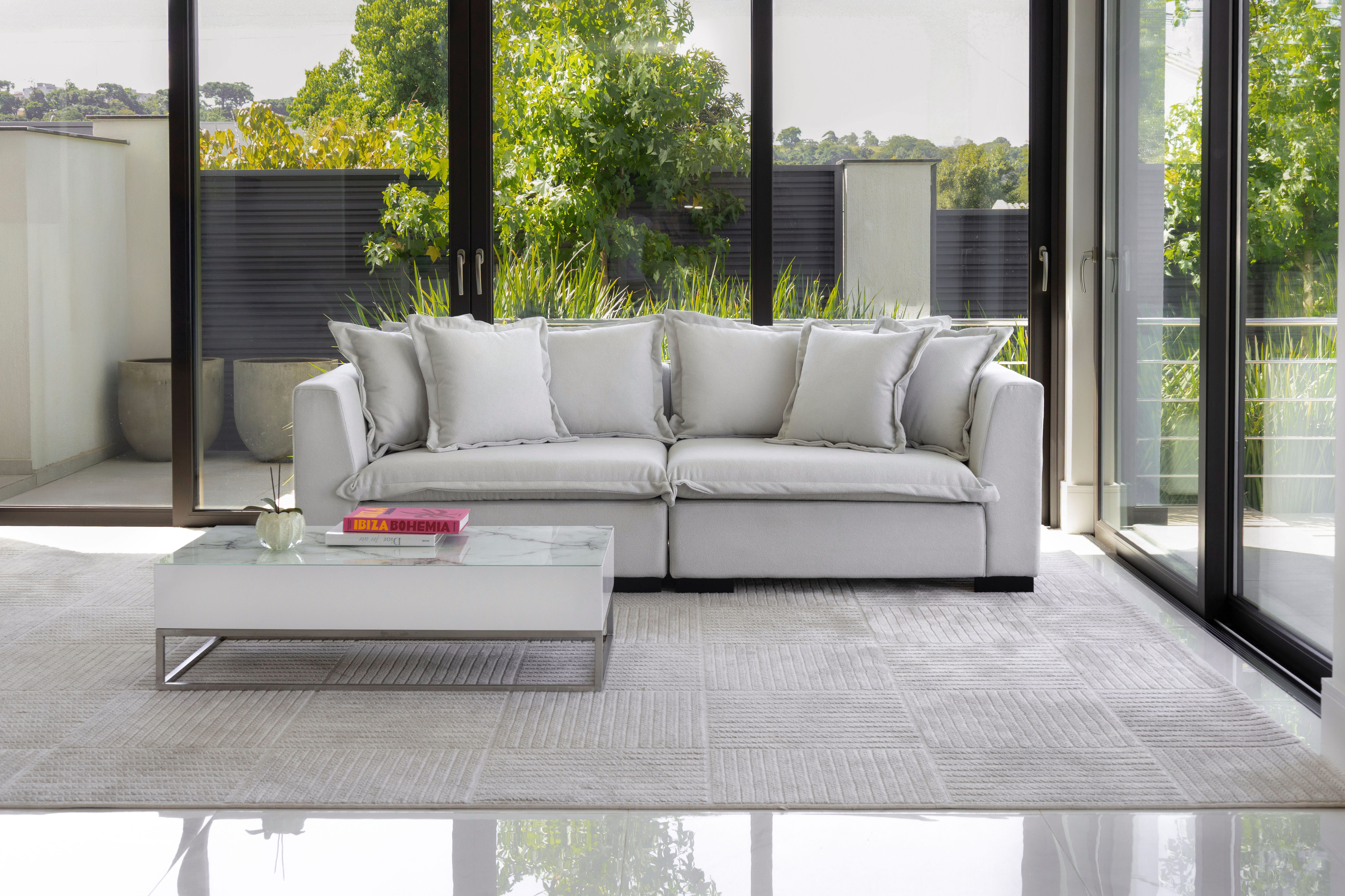 Sofá modular branco com mesa de centro baixa e revistas, ambiente contemporâneo